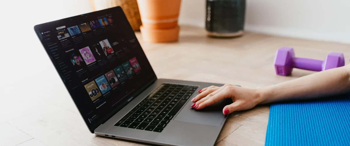 Online-Coaching in der Nähe: Eine Frau sitzt mit Laptop an einem modernen Schreibtisch, umgeben von Pflanzen, symbolisiert digitales Coaching.