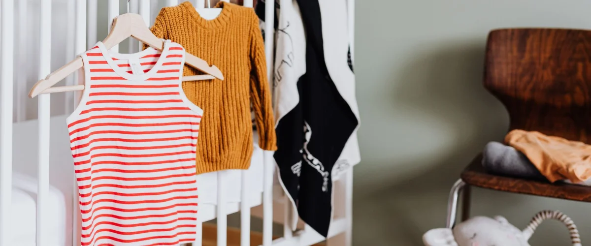 Babyausstattung finden – Eine lächelnde werdende Mutter hält ein kleines Paar Babyschuhe in den Händen, um Babyausstattung zu finden.