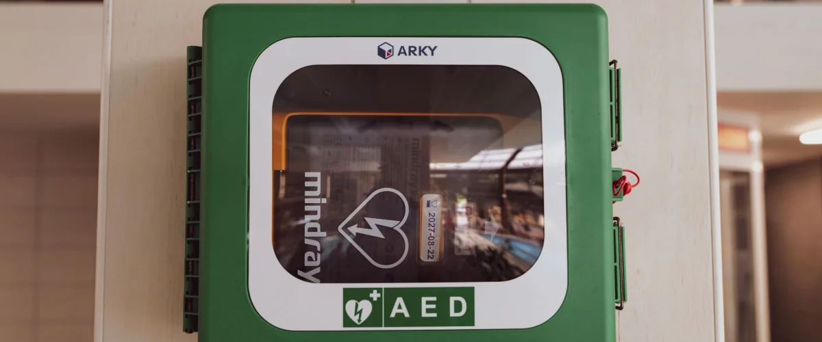 Defibrillator Grundlagen – Zwei Hände positionieren Elektroden eines AEDs auf dem Brustkorb, um Defibrillator Grundlagen zu demonstrieren.