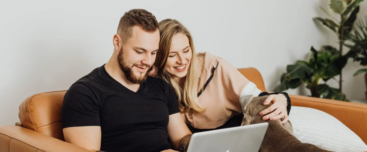 Wohnsitzanmeldung online – Person nutzt Laptop für Wohnsitzanmeldung online mit Smartphone und Ausweis im Vordergrund.