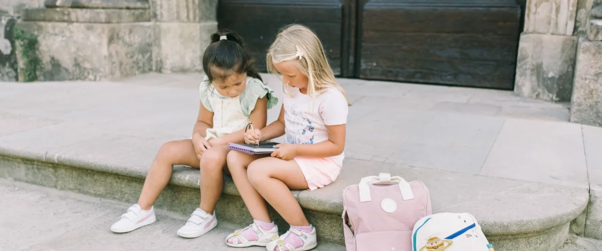 Schuleinführung Tipps: Ein strahlendes Kind mit neuem Schulranzen und Schultüte vor dem Schulgebäude, bereit für den ersten Schultag.